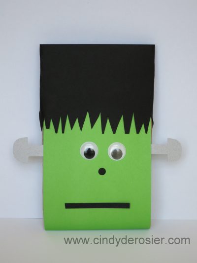 To make a Microwave Popcorn Frankenstein, you need: a package of microwave popcorn, cardstock or construction paper (green, black and silver/grey), large googly eyes, scissors, hole punch, and glue.