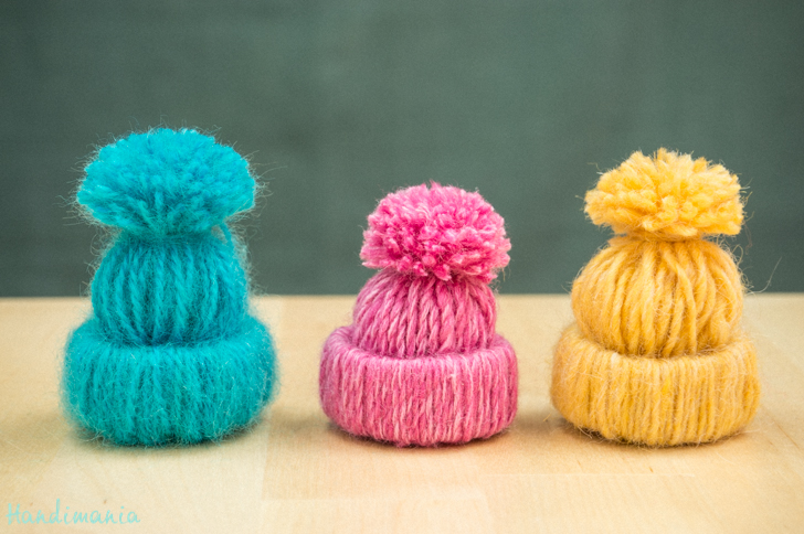 These tiny hats are made of yarn and toilet paper tubes.