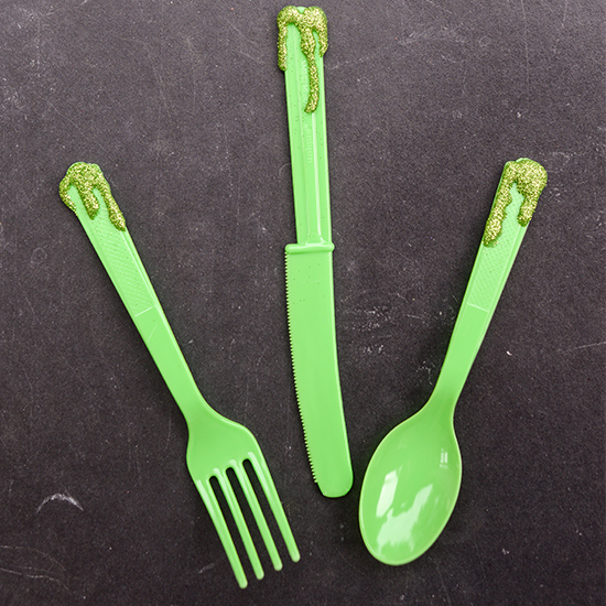 A glue gun and some glitter turn plain plastic flatware into something special and spooky for your Halloween party.